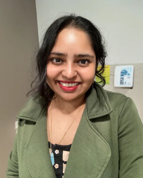 Portrait of Jayeeta "Crystal" Chakrabarti smiling in an olive green jacket.